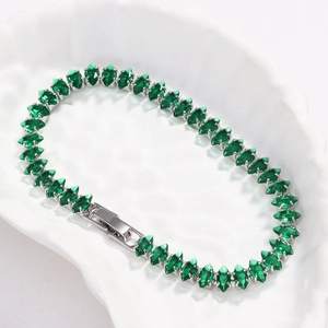 Dettaglio del bracciale tennis elegante con zirconi verdi taglio marquise su piatto bianco.