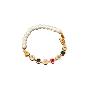 Bracciale vintage dorato con perle e pietre di zircone colorate a cuore su sfondo bianco