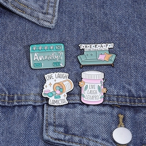 Set of four metal enamel pins featuring lemon bubble labels pinned on a blue denim jacket