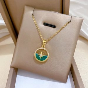 Macro view of gold plated necklace with green starburst pendant in a jewelry box