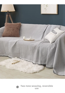 Detailed view of gray waffle weave sofa cover with decorative tassels and thick texture