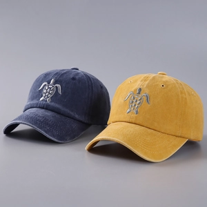 Close-up of detailed sea turtle embroidery on washed cotton baseball caps in navy and yellow