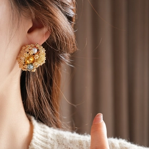 Gros plan détaillé d'une boucle d'oreille vintage en or avec perles et pierres jaunes