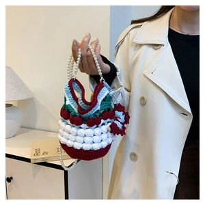 Detail of hand-knitted cherry bucket bag with white yarn texture and pearl handle