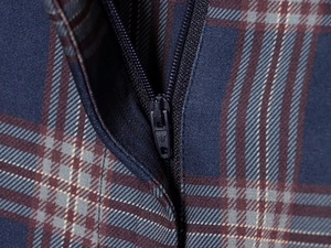 Close-up of smooth metal zipper on navy blue and reddish-brown plaid woven fabric
