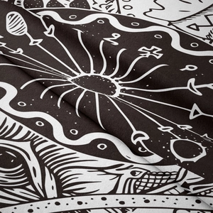 Close-up of black and white bohemian tapestry showing intricate tribal sun and eye motifs