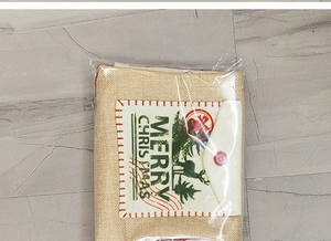 Detail of burlap Christmas gift bag with Merry Christmas print and button closure