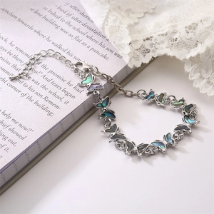 Detail view of silver butterfly bracelet with iridescent shell inlay on a book background