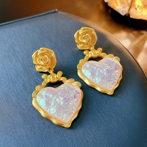 Détail de boucles d'oreilles cœur vintage en or avec résine irisée et motif rose