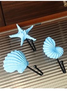 Detail of star, scallop and conch resin ocean wall hooks on black metal hooks