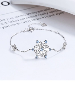 Macro detail of 925 silver snowflake bracelet with light blue gemstones on book pages