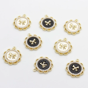 Detail of round floral pendants with gold bows and tiny pearls in black and white