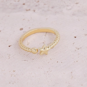 Macro shot of gold-plated open ring with textured band and star charm detail