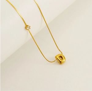 Detail of a 3D bubble letter D gold pendant necklace with a small round zircon accent