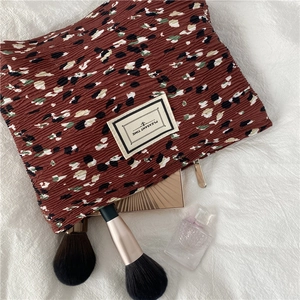 Detail of red-brown crinkle chiffon cosmetic bag with speckle print and pleasant time label