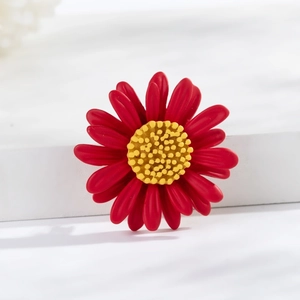 Macro detail of red daisy brooch with matte petals and yellow resin core texture