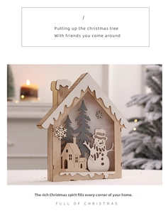 Detail of laser-cut wooden Christmas cabin ornament with snowman and pine tree motifs