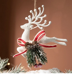 Detail of white reindeer ornament with pine cones, red berries and festive ribbon