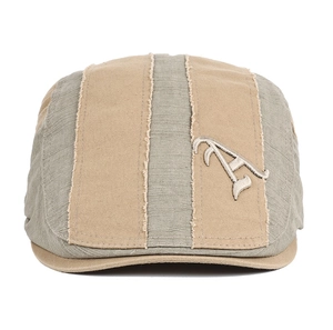 Detail view of khaki and grey patchwork beret with letter A embroidery and frayed edges