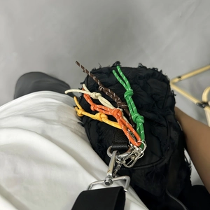 Fashionable woven rope keychain on black pleated crossbody bag with colorful cords