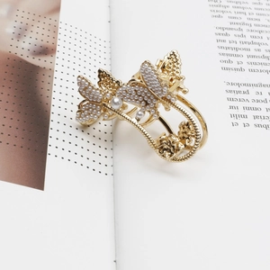 Goldene Schmetterlings-Haarklammer aus Metall mit Perlen und Strass auf einem Buch