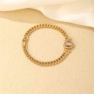 Detail view of a gold Cuban link bracelet with a sparkling zircon encrusted charm