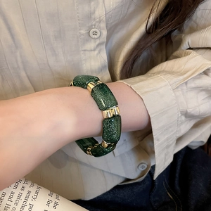 Close-up of green shimmering pillar beads bracelet with gold spacers on a wrist
