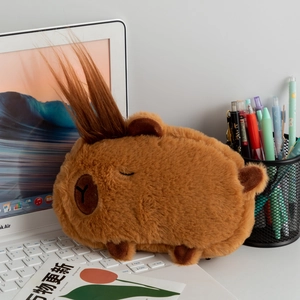 Close-up of a plush Capybara pencil case with funny hair on a white laptop keyboard