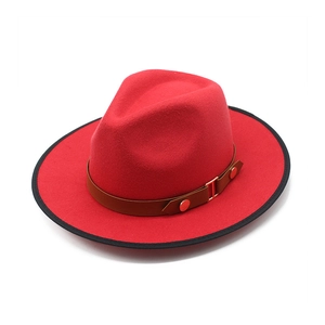Detail of red wool fedora with black trim, brown leather strap and gold buckle