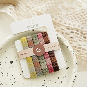 Detailed view of five seamless Morandi colored knitted elastic hair ties on a card