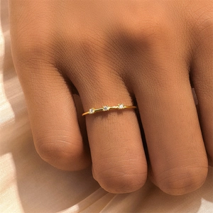 Detailed view of a gold minimalist thin ring with three sparkling clear diamonds on a finger