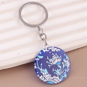 Detail of floral acrylic keychain with blue white pattern on wavy display stand