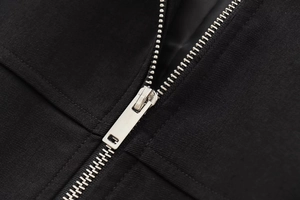 Macro detail of high-quality silver metal zipper on premium black twill fabric jacket