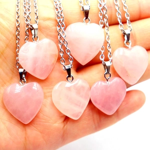 Close-up of pink heart-shaped crystal necklaces with silver chains held in hand