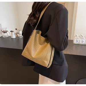 Close-up of yellow woven texture tote bag with wide shoulder strap on a model