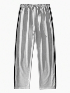 Detail of light grey jogger pants featuring black side stripes and ribbed ankle cuffs