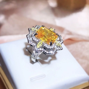 Luxurious silver cocktail ring with large yellow rectangular gem and marquise halo detail