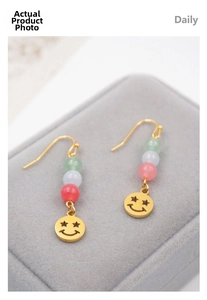 Close-up of ethnic drop earrings featuring gradient jade beads and a golden star-eye smile charm