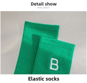 Close-up of green ribbed knit cotton socks featuring white letter B embroidery detail