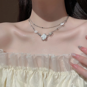 Detailed view of silver double-layered floral necklace with pearls on a female model