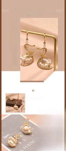 Detail view of swan-shaped baroque pearl earrings with 18K gold-plated wire craft