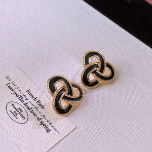 Detailed close-up of French vintage black enamel and gold interlocking knot stud earrings