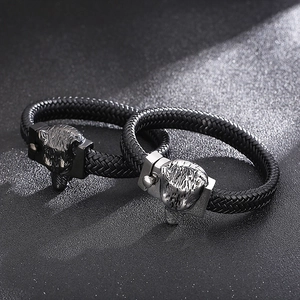 Macro detail of braided leather bracelets with intricately carved wolf head metal clasps