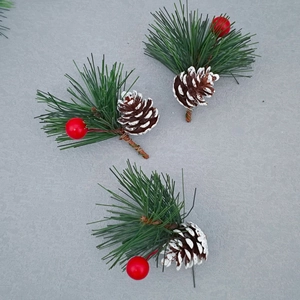 Artificial Christmas pine needles with snowy cones and red berries on a stone background