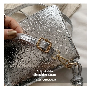 Detail of silver stone-textured bag showing the adjustable strap with gold hardware