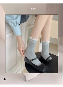 Détail de chaussettes gris clair à côtes avec bordure en dentelle blanche et souliers