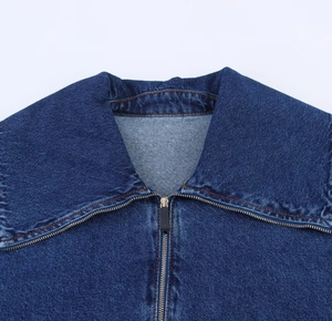Dettaglio della giacca in denim blu che mostra il bavero e la chiusura con zip in metallo