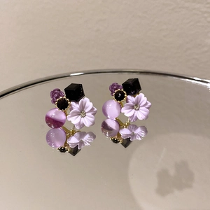Macro view of purple flower earrings with resin petals and shimmering rhinestone center