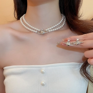 Detail view of double-layer pearl necklace with sparkling zircon saturn orb pendant