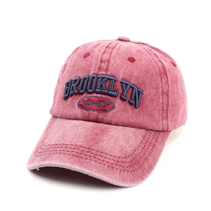 Detail view of pink washed denim baseball cap with navy Brooklyn embroidery